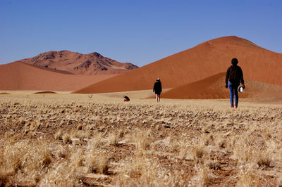 People on desert against clear sky