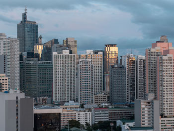 Modern buildings in city against cloudy sky