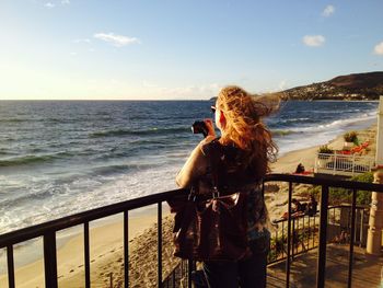 Woman looking at sea against sky