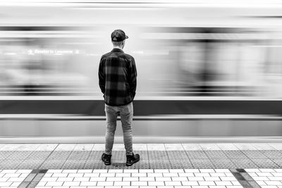 Rear view of man standing at railroad station