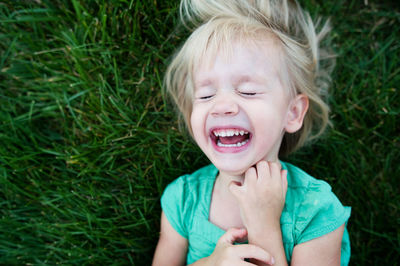 Overhead view of girl crying while lying on grassy field at park