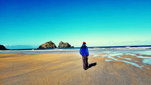 Man standing on beach against clear blue sky