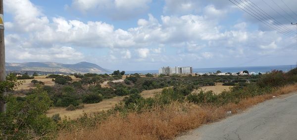Panoramic shot of road by buildings against sky