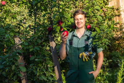 Portrait of young woman standing amidst plants