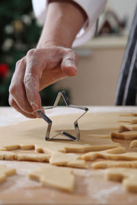 Cropped hands of chef cutting dough with pastry cutter at table