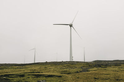 Windmills on field against clear sky