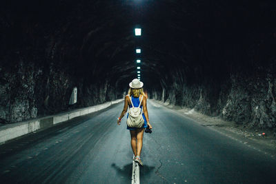 Rear view of woman walking in tunnel