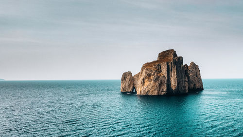 Rock formation in sea against sky