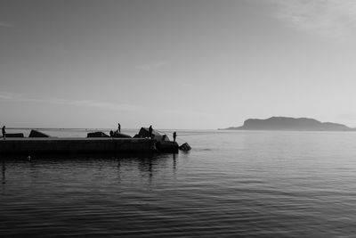 Silhouette people in sea against sky