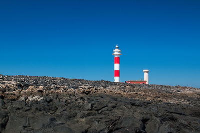 Lighthouse by street light against clear sky