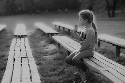 Side view of woman sitting on bench in park