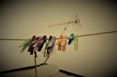 Close-up of clothespins hanging on clothesline against wall