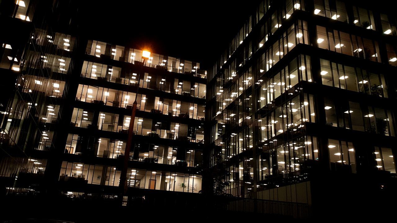 LOW ANGLE VIEW OF ILLUMINATED BUILDINGS AGAINST SKY AT NIGHT