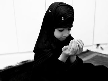 Close-up of girl wearing hijab praying at home