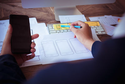 Midsection of man using mobile phone on table