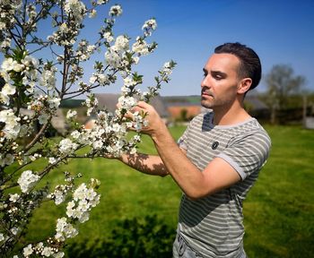 Full length of young man against white flowering tree