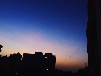 Low angle view of silhouette buildings against sky at sunset