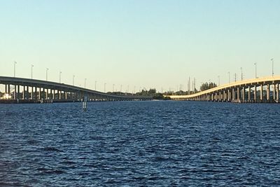 Bridge over calm sea against clear sky