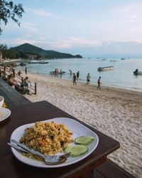 Close-up of food on table at beach against sky