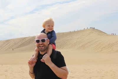 Portrait of smiling boy on sand at beach against sky