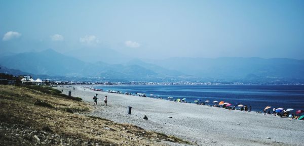 Panoramic view of people on beach against sky