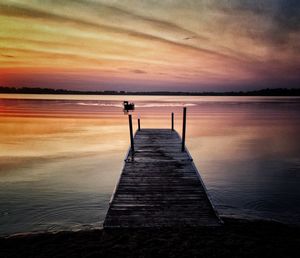 Pier on beach against sky during sunset