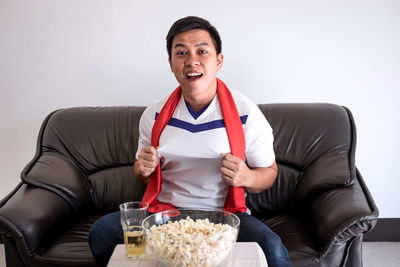 Portrait of young man watching sport while sitting on sofa at home