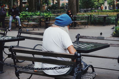 Rear view of senior man sitting on bench at park