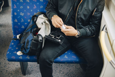 Midsection of man doing blood test while sitting in train