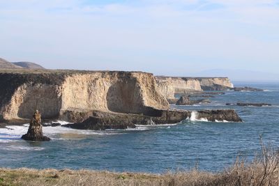 Scenic view of sea by cliff against sky