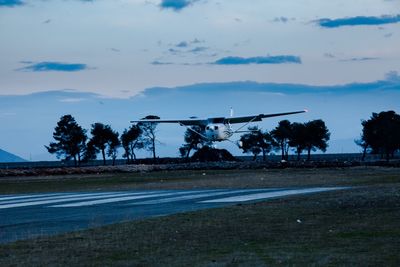 Airplane flying over road against sky