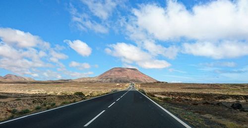 Scenic view of road by mountains against sky