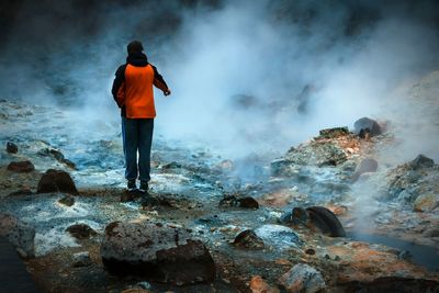 Man standing on rock formation by hot springs