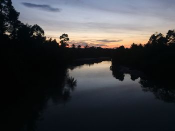 Reflection of silhouette trees in lake against sky during sunset