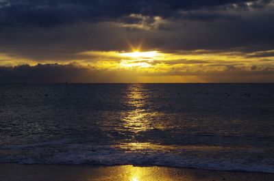 Scenic view of sea against dramatic sky during sunset