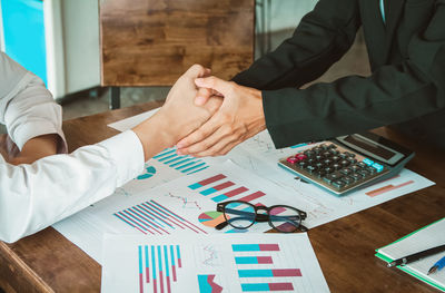 Midsection of business colleagues shaking hands in office