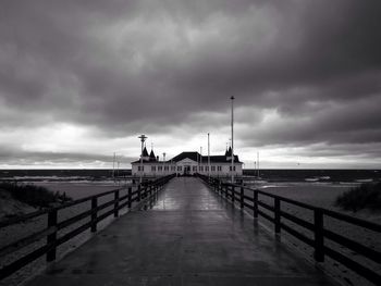 Pier on sea against cloudy sky