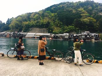 People on bicycle by river against trees