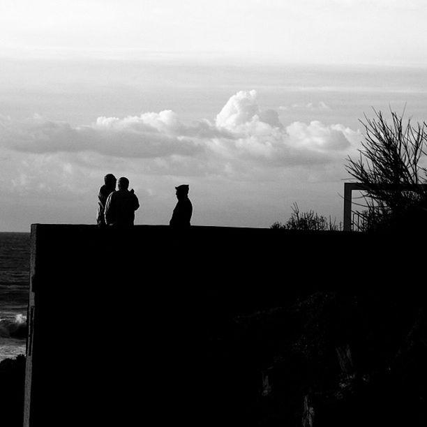 silhouette, men, lifestyles, sky, togetherness, leisure activity, sea, water, person, standing, bonding, cloud - sky, sitting, nature, rear view, sunset, beauty in nature, tranquility