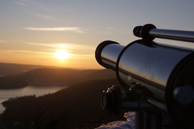 Close-up of coin-operated binoculars against sky during sunset