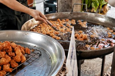 Close-up of human hand frying food for sale