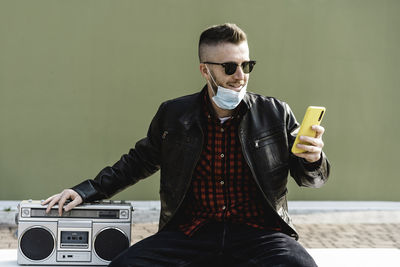 Young man using mobile phone while sitting on camera