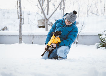 Smiling man with dog on snow covered land during winter