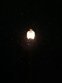 Low angle view of illuminated light bulb against sky at night