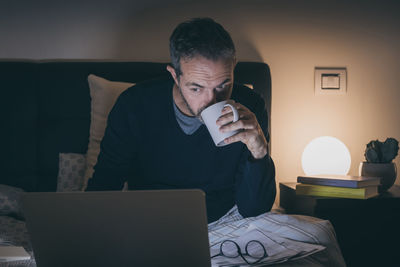 Man works with laptop lying on bed. male home working remote office sitting in bedroom use devices