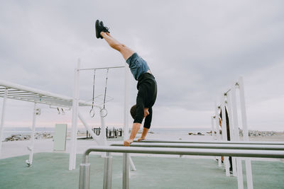 Low angle view of woman standing on railing against clear sky