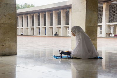 Side view of woman in hijab reading book at mosque