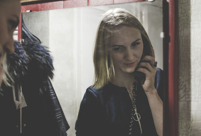 Reflection of woman talking on telephone in mirror