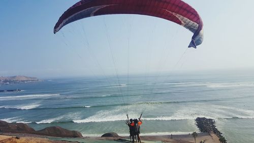 People flying over sea against sky