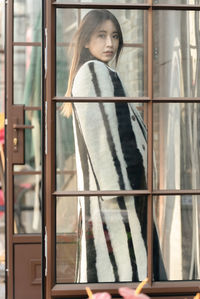 Young woman looking through window